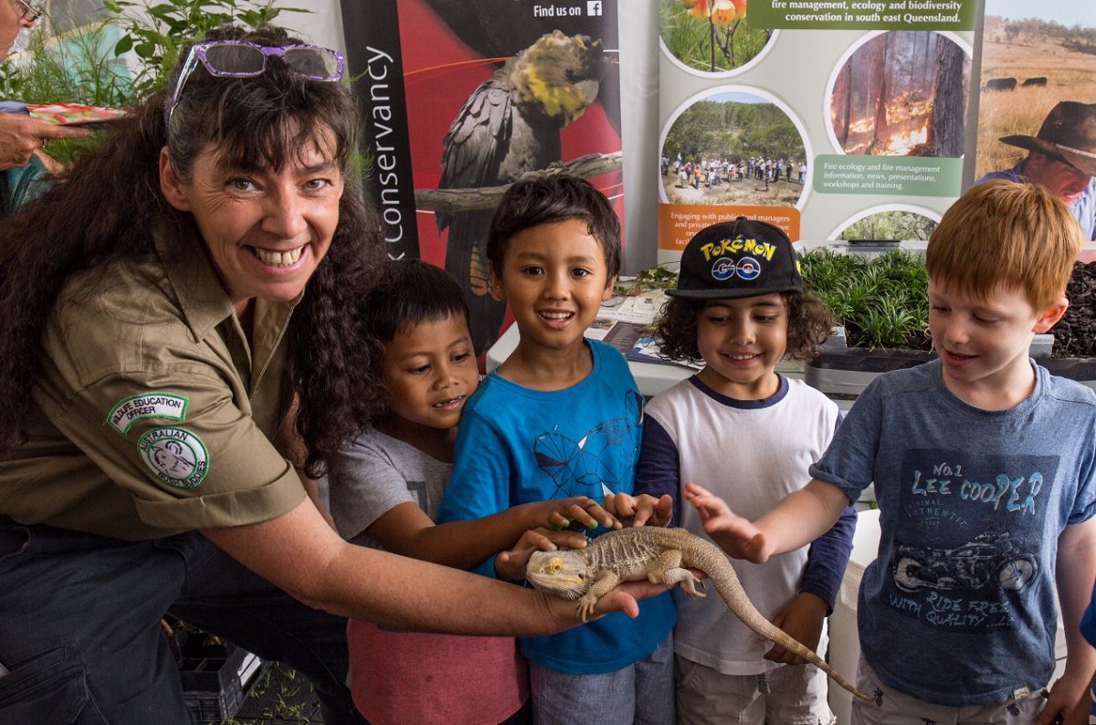 Kids and a wildlife education officer touching an iguana
